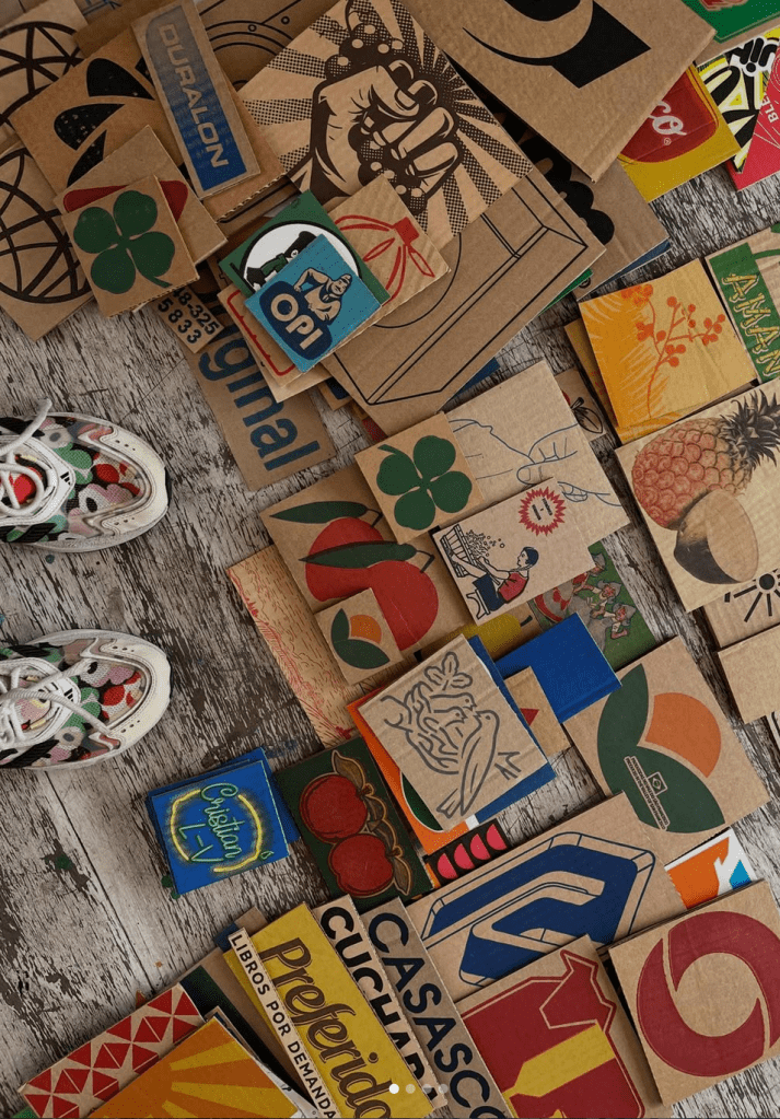 Artist Elisa Strada stands above piles of graphic and colorful cardboard pieces. 