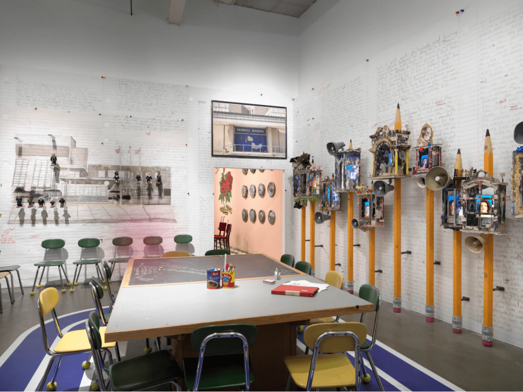 An installation inside a recreated school classroom with a combination of found educational items, and artistically rendered objects.